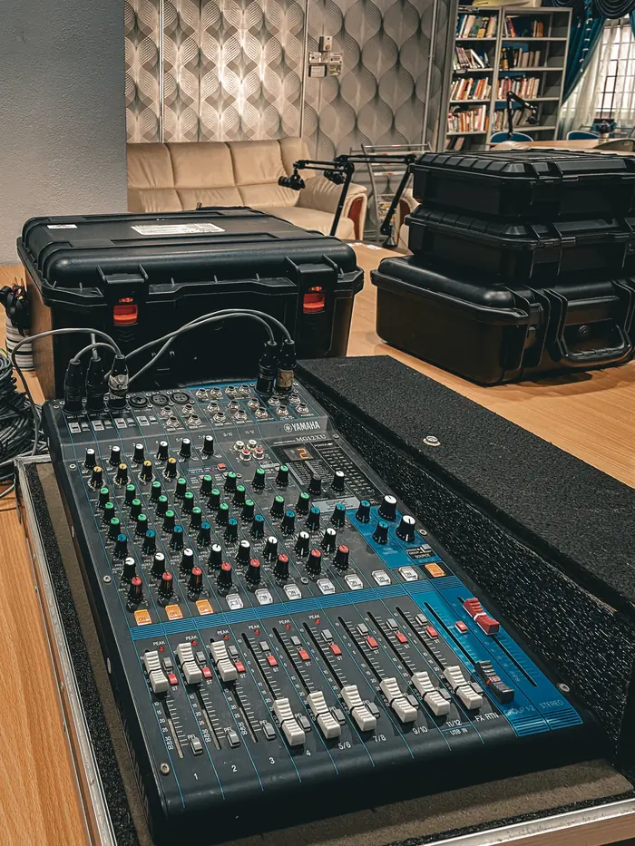 An analogue mixing console on a stand, flight cases stacked behind it